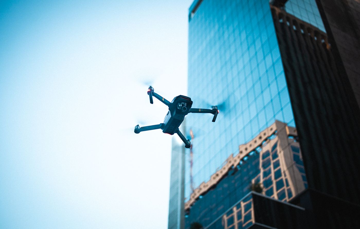 Security drone in sharp focus flying near a modern city skyscraper