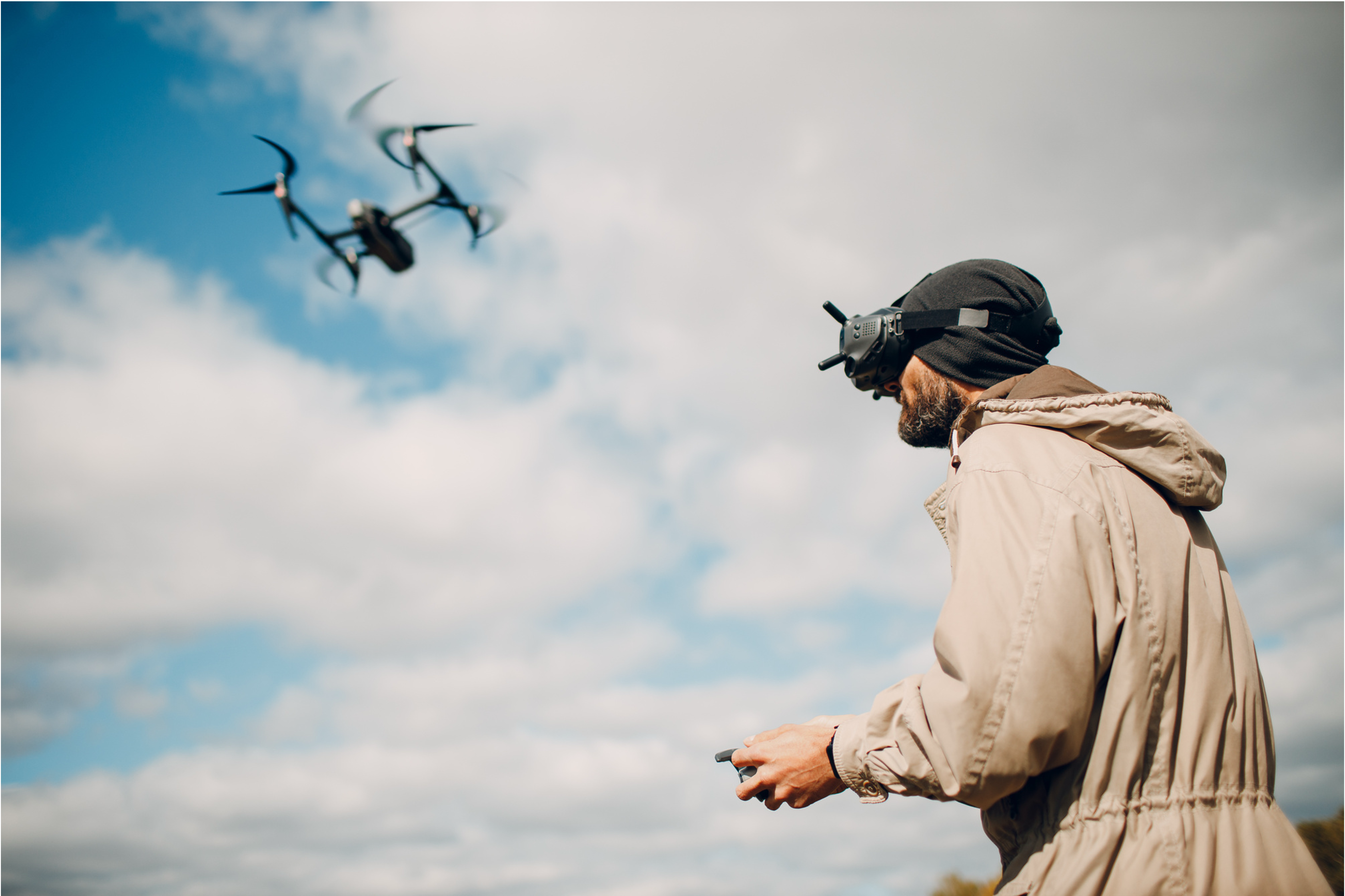 Operator flying the HaytHive drone via FPV goggles against an open sky